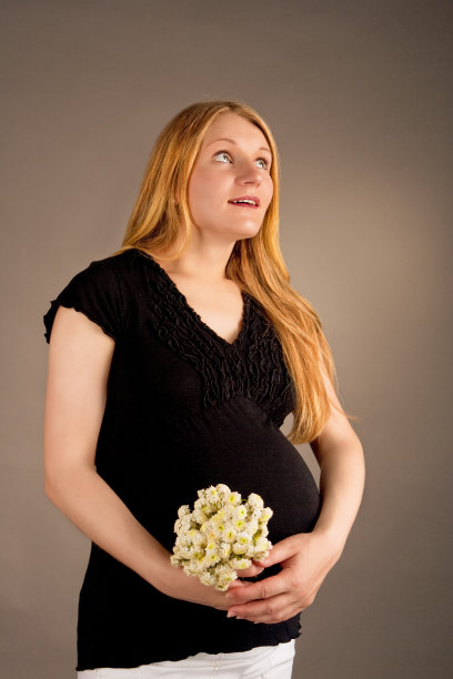 惊喜的年轻怀孕金发美女和一束花图片下载