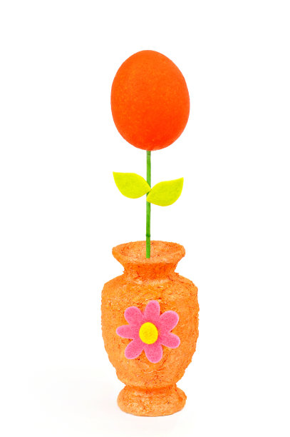 复活节彩蛋放在橙色花瓶里，白色花瓶上图片下载