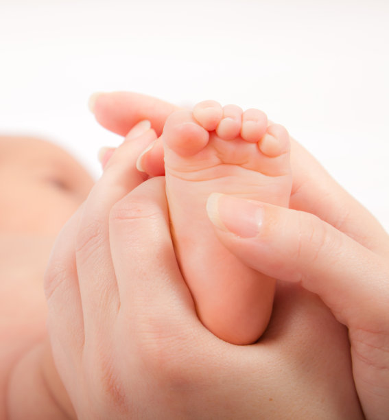 女人用手按摩小婴儿的脚，近处素材图片