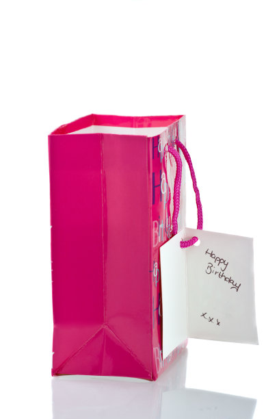 粉红色的礼物袋，上面有生日祝福语标签。图片下载