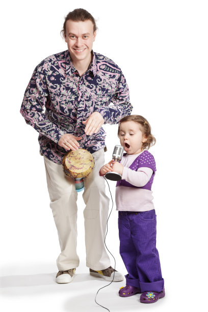 父亲弹奏手鼓，女儿对着麦克风唱歌。图片下载