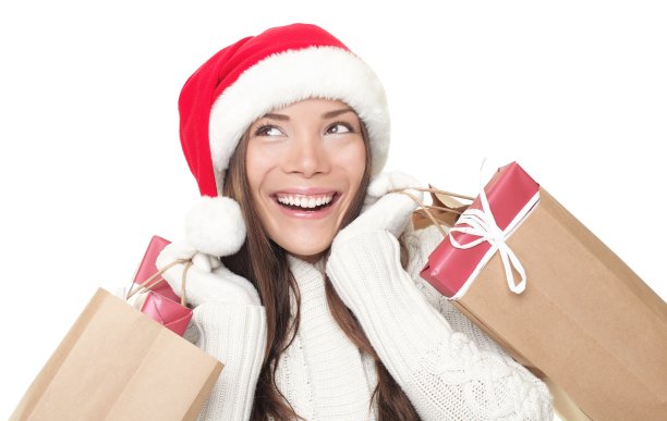 年轻女子戴着圣诞帽，每只手拿着礼物袋图片下载