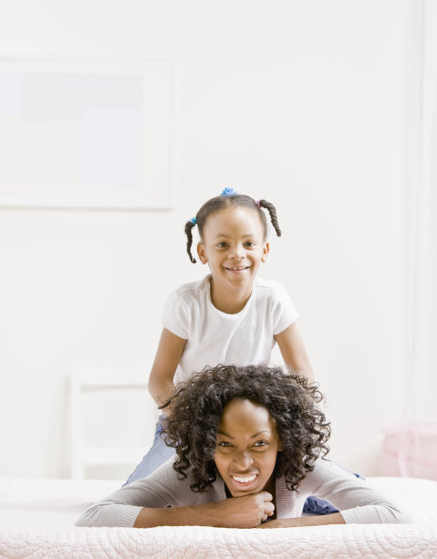 慈爱的母亲和顽皮的女儿躺在床上图片下载