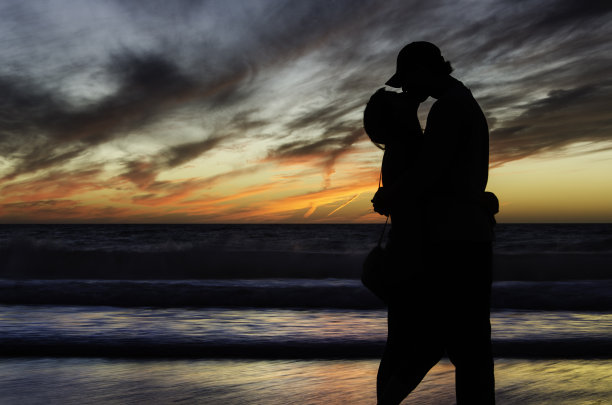 在美丽的日落前，一对接吻的情侣剪影图片下载