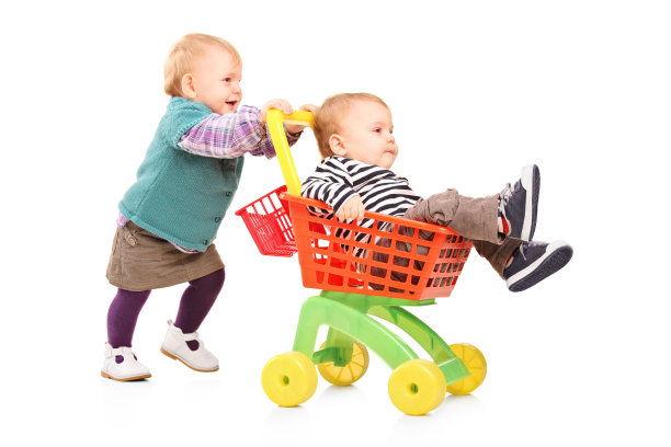 蹒跚学步的小女孩推着玩具车里的双胞胎弟弟图片下载