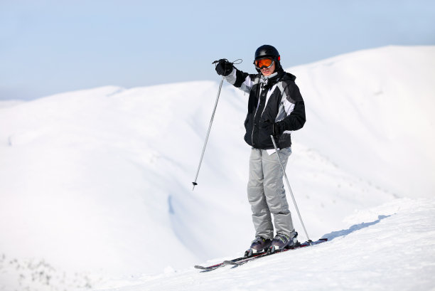 滑雪者站在山顶指着什么东西图片下载