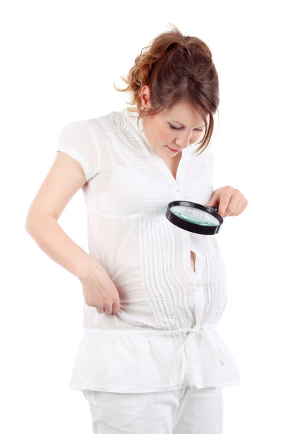 一名白衣孕妇透过放大镜看腹部图片下载