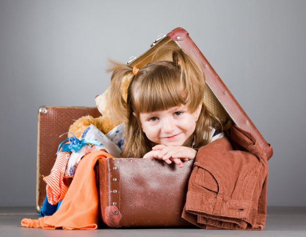 女孩愉快地坐在一个旧手提箱里图片下载