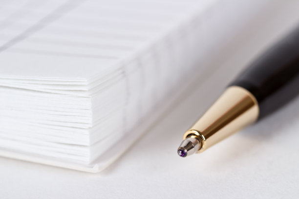 金色和黑色的金属笔靠近打开的记事本图片下载