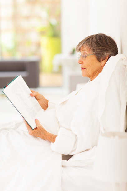 老妇人躺在床上看书图片下载