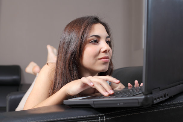 一个坐在沙发上拿着笔记本电脑的美女图片下载