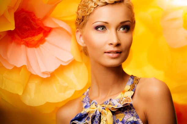 穿着鲜艳衣服的金发女人站在大黄花中间图片下载