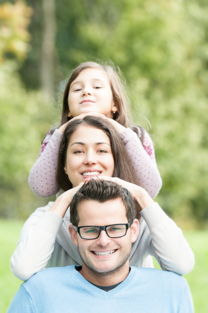 快乐的父母和美丽的女儿在公园。图片下载