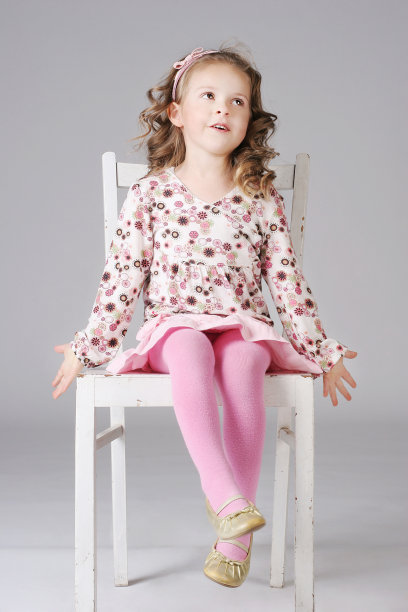 可爱的小女孩坐在白色的椅子上，摆姿势。图片下载