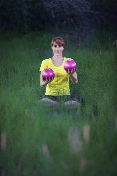瑜伽姿势的女人，举起举起银色健身球图片下载
