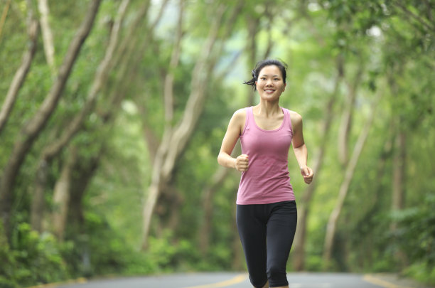 年轻的亚洲女人在森林里慢跑图片下载