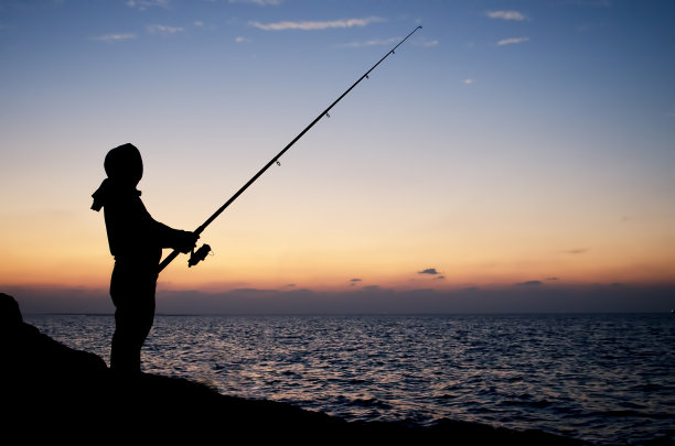 日落时分，在海边钓鱼的人的剪影图片下载