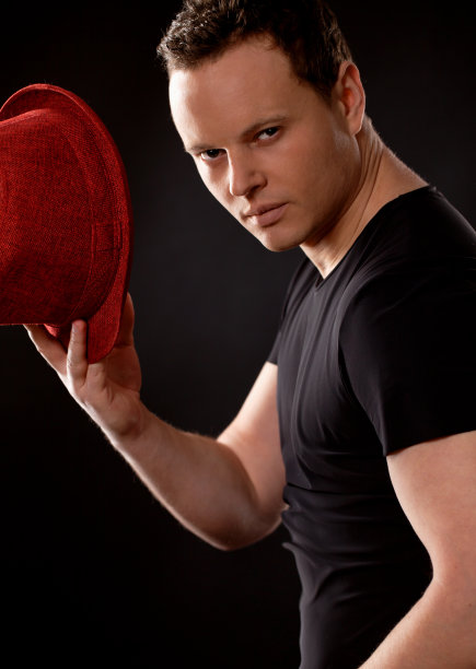 英俊的舞者拿着红色的帽子。愤怒的问候。图片下载