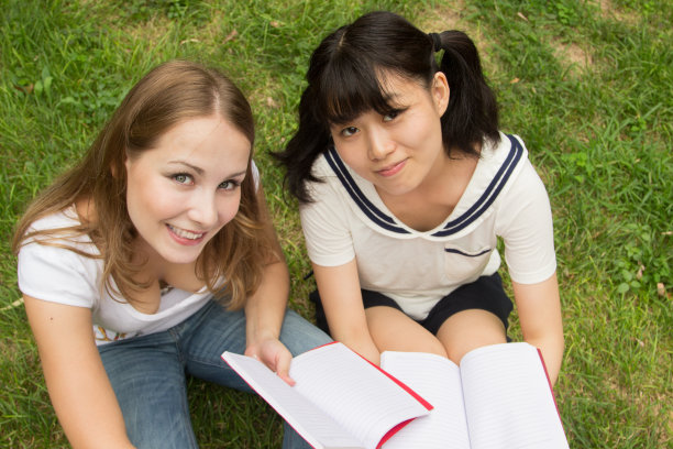 快乐大学女学生坐在户外的草地上图片下载