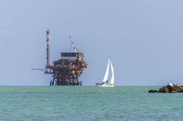 驶过海上石油平台的游艇图片下载