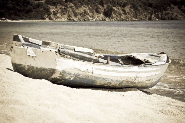 孤独的渔船在海边的沙滩上。复古的照片图片下载
