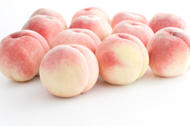 白桌上放着一打毛茸茸的圆桃子素材图片