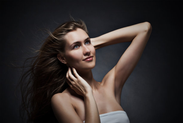 头发飘动的漂亮女人。在黑暗的背景。图片下载