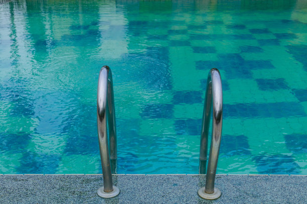 在蓝色的游泳池里抓住栏杆图片下载