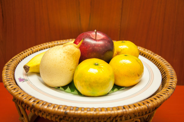 水果和树叶装在一个漂亮的篮子里，放在木桌上图片下载