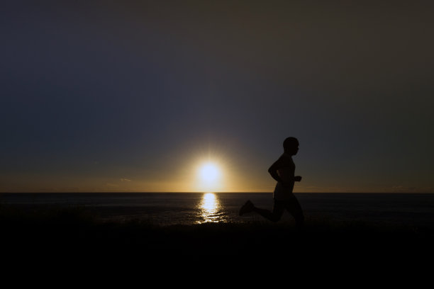 日落时，沿着地平线慢跑者的剪影图片下载
