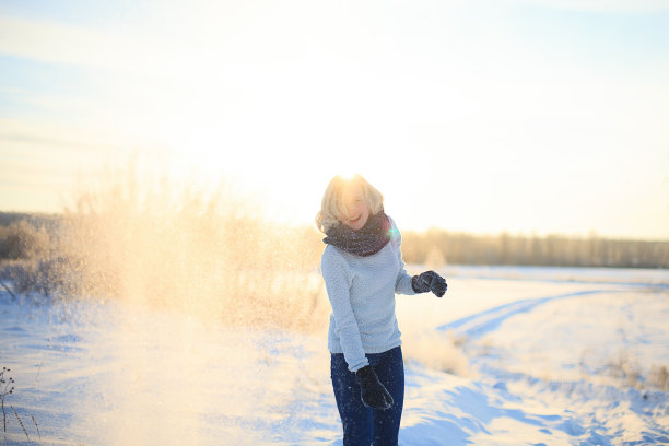 美丽的年轻女孩在冬天玩雪，并高兴。素材图片
