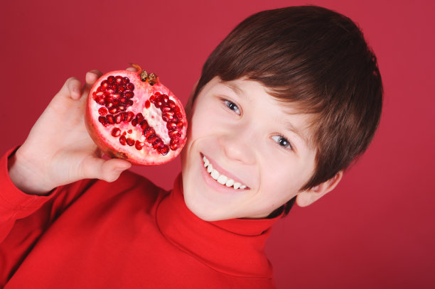 一个小男孩拿着一块石榴图片下载