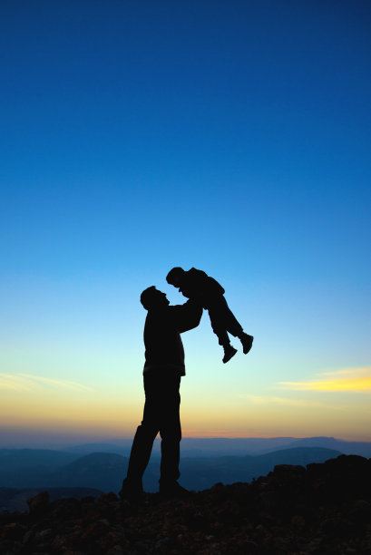 日出时父亲抱儿子上山的剪影图片下载