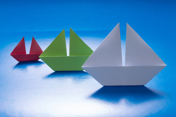 在蓝海上航行的纸船组。折纸船。图片下载