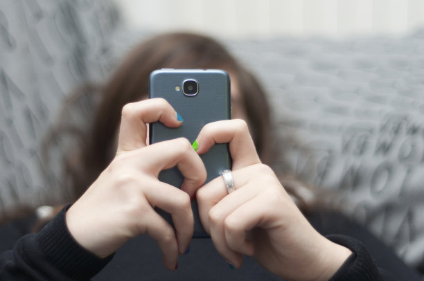 躺在沙发上玩手机的女孩图片下载