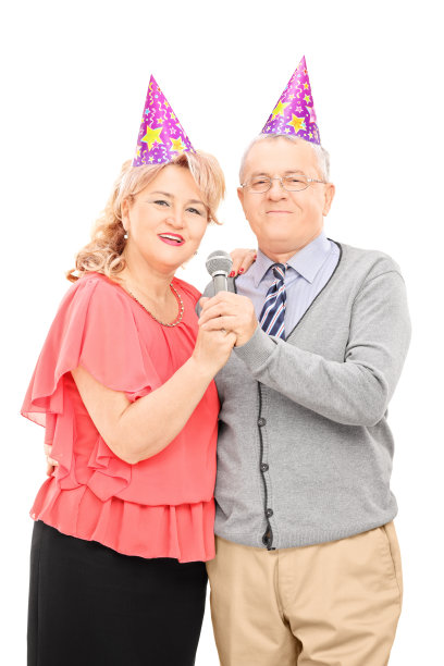 戴派对帽的成熟情侣对着麦克风唱歌图片下载