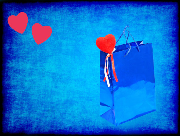 蓝色的情人节礼物袋和红色的心在蓝色肮脏的背景。图片下载