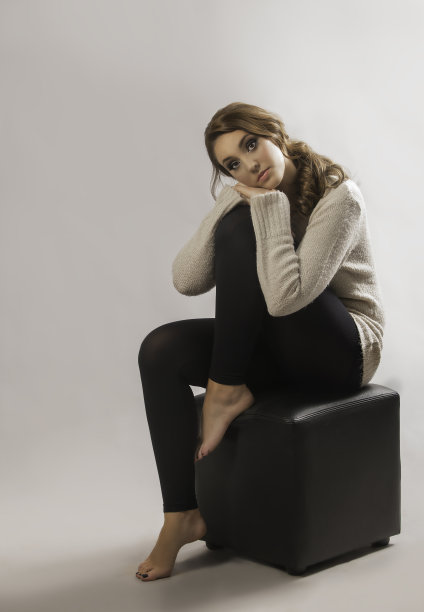 深色头发的女人在运动衫和紧身衣靠在她的腿上图片下载