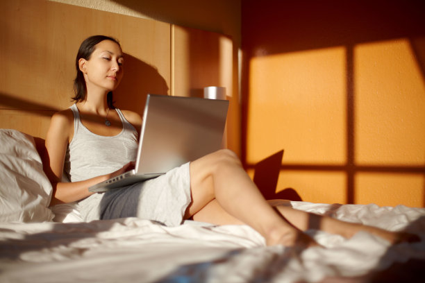 漂亮女孩躺在床上，拿着笔记本电脑图片下载