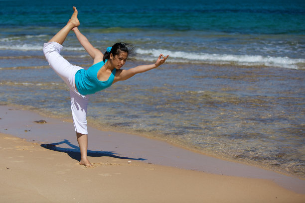 年轻女子在海滩上练习瑜伽图片下载
