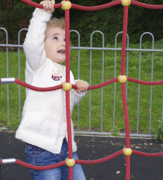 小孩子爬上红色的绳架。图片下载