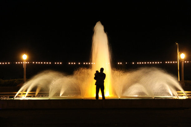 一个带着孩子的男人站在饮水器前图片下载