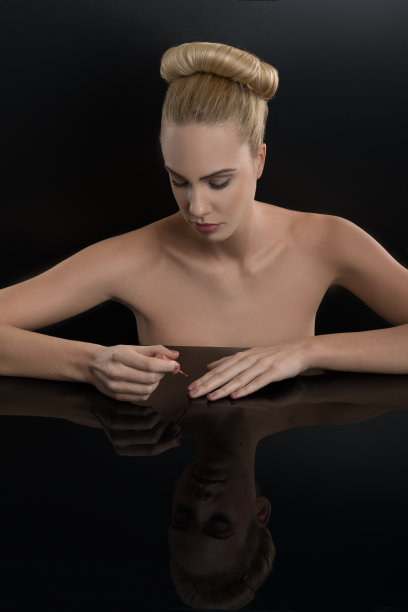 金发女人在黑镜子上涂指甲油…美。图片下载