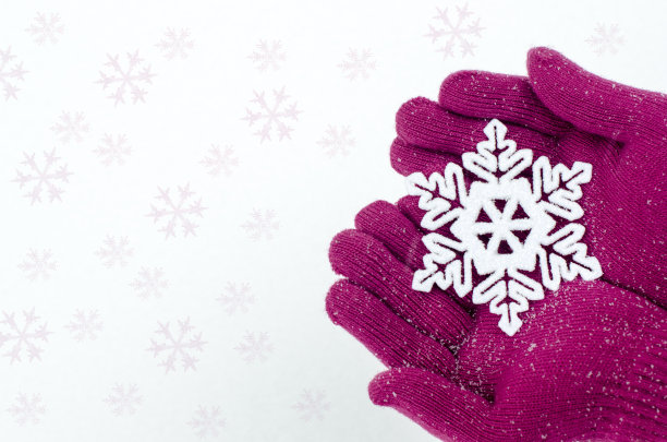 近距离观察戴着粉红色手套捧着大雪花的手。图片下载