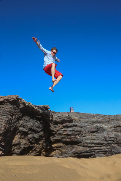 一个人模仿一只鸟，从岩石上跳下来。图片下载