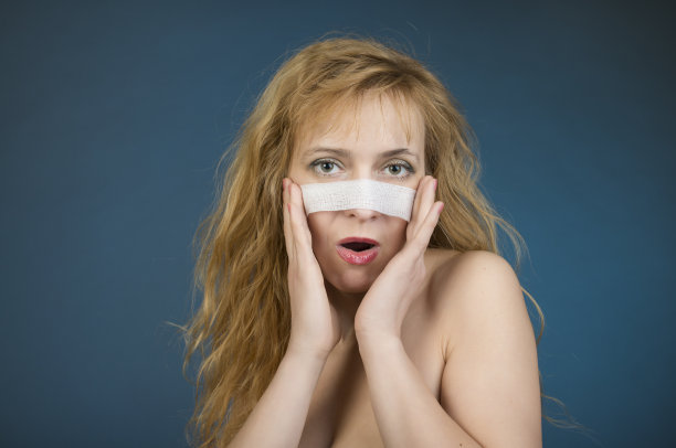 整形手术的概念。脸上缠着绷带的女人。图片下载