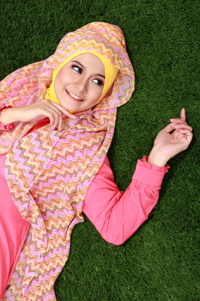 年轻的穆斯林女孩躺在草地上图片下载