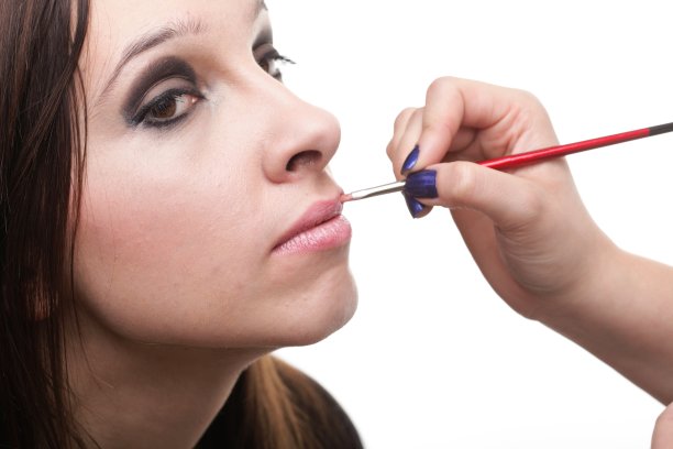 漂亮的年轻女子在唇上涂口红图片下载