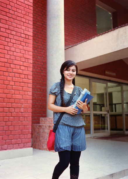 美丽的大学生在楼外微笑。图片下载