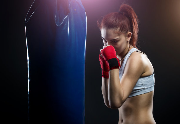 年轻女子在拳击袋上拳击图片下载